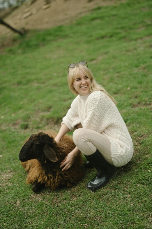 a woman kneeling down petting a brown and black sheep, an album cover, inspired by Leila Faithfull, wearing casual sweater, zoe kazan, blonde swedish woman, profile image