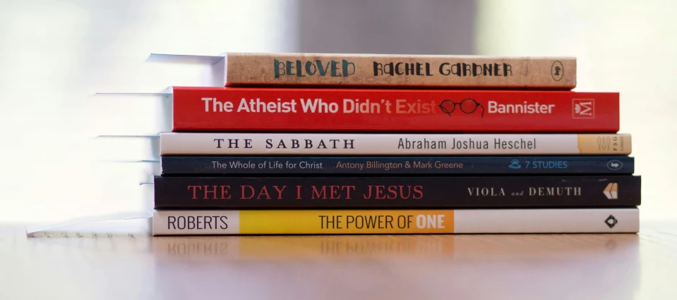 a stack of books sitting on top of a table, religious imagery, lgbtq, slightly minimal, raphaelites