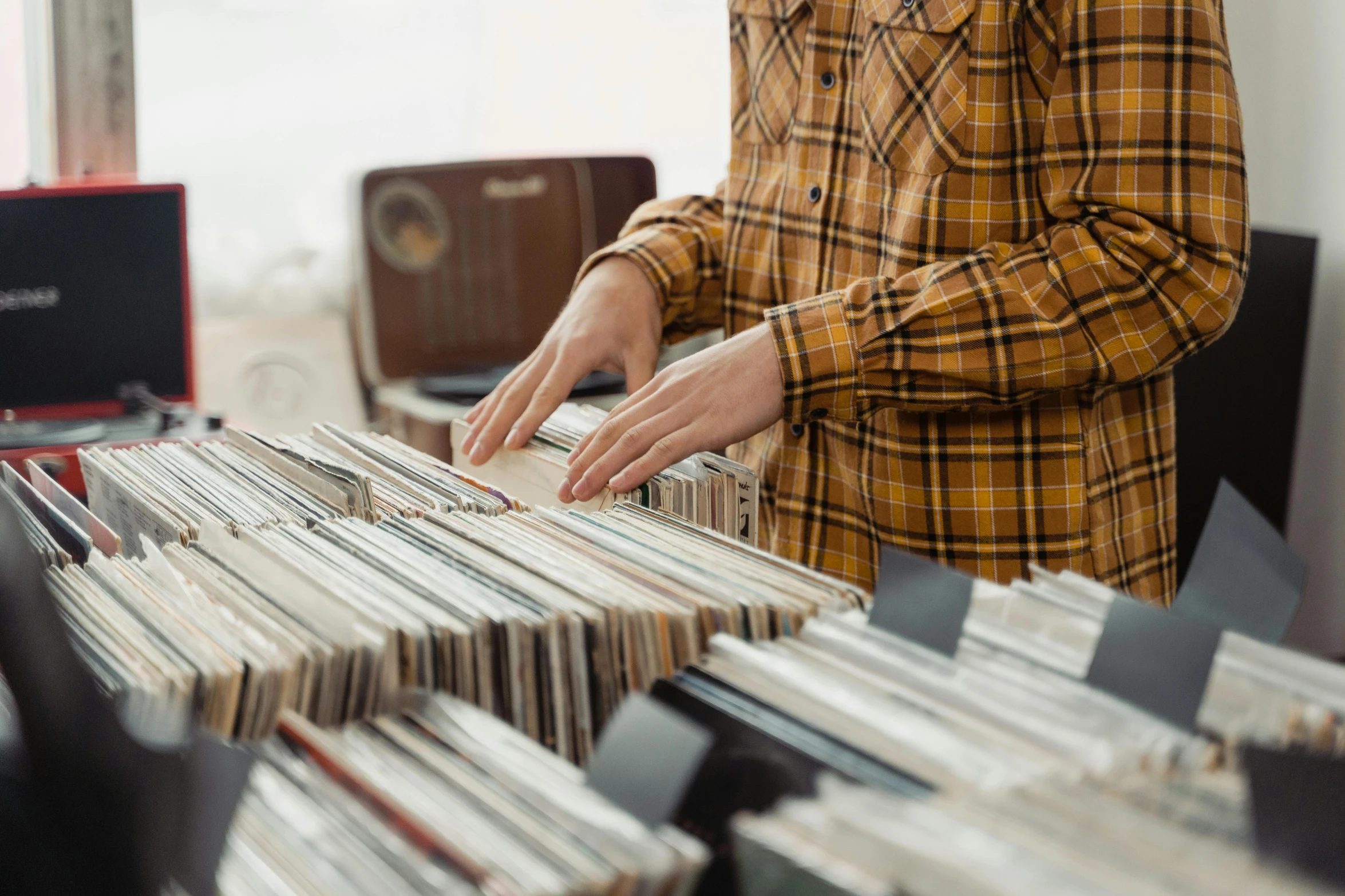 a person standing in front of a table full of records, trending on pexels, private press, australian, people shopping, corduroy, super detailed image