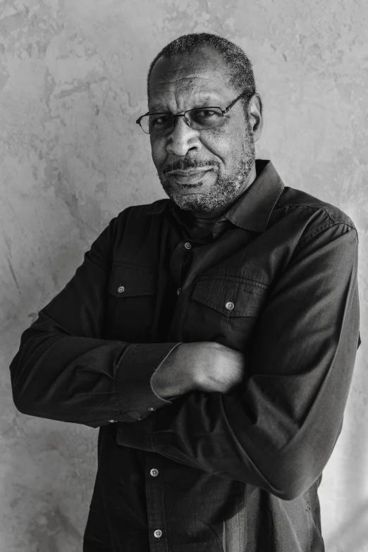 a black and white photo of a man with his arms crossed, inspired by Ismail Gulgee, anthony avon, portrait image, slightly smirking, george floyd