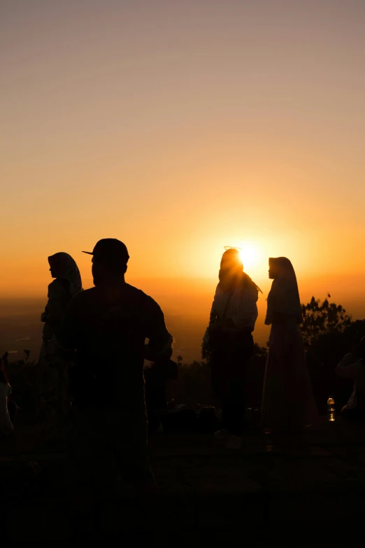 a group of people standing on top of a hill, during a sunset, at borobudur, city views, during an eclipse