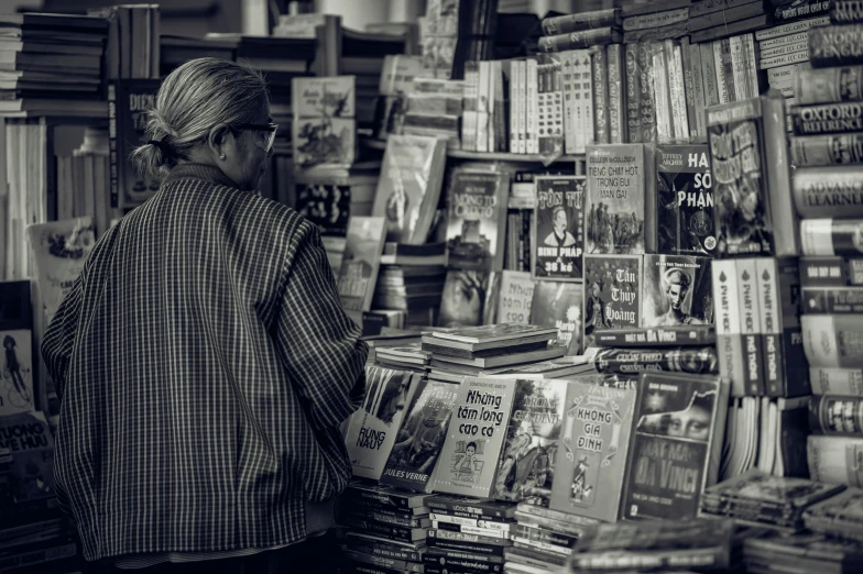 a woman standing in front of a book store, a black and white photo, pexels contest winner, happening, old lady, stack of books on side table, old lady cyborg merchant, from reading to playing games