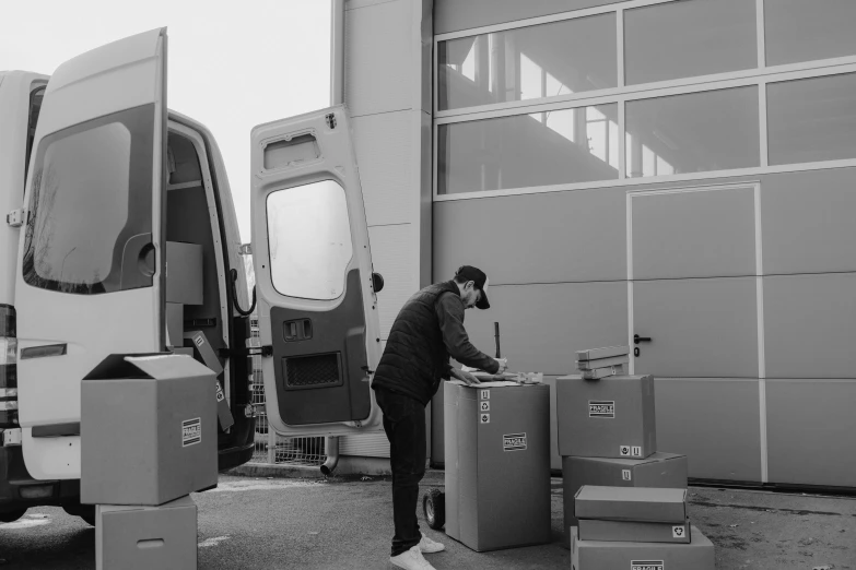 a black and white photo of a man unloading boxes, high-quality, vesa-matti loiri, bussiere, high details!