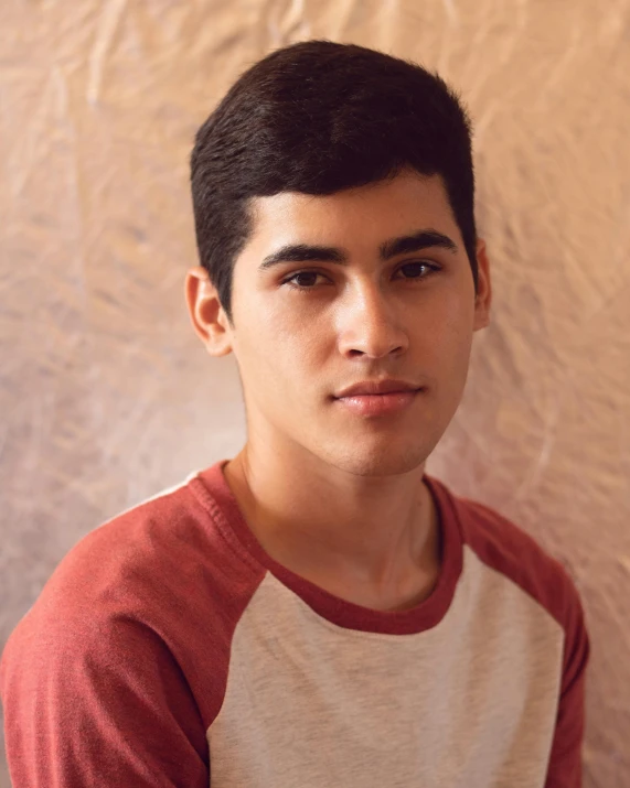 a young man wearing a red and white shirt, by Ismail Acar, trending on unsplash, transgender, assyrian, lovingly looking at camera, grayish