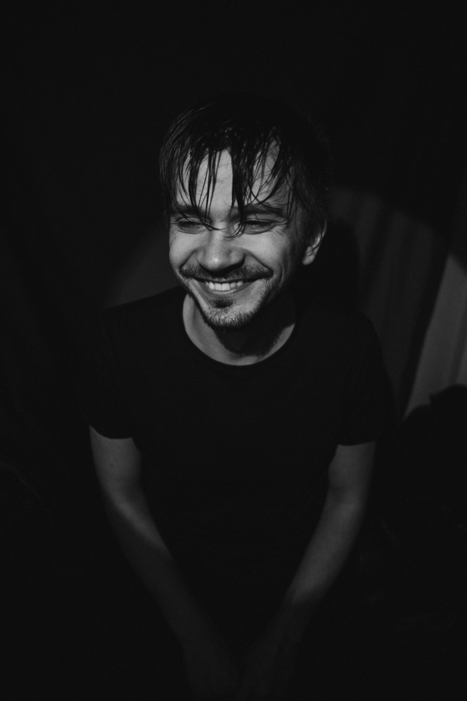 a man that is sitting down in the dark, a black and white photo, giddy smirk, symmetrical face orelsan, azamat khairov, smiling playfully
