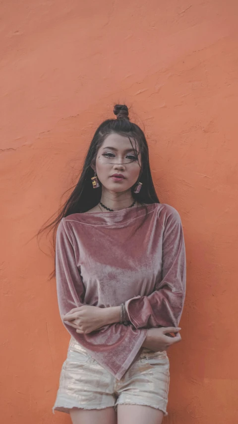 a woman standing in front of an orange wall, an album cover, inspired by Elsa Bleda, trending on pexels, beautiful asian woman, 15081959 21121991 01012000 4k, grey, malaysian