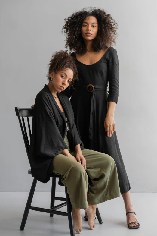 two women sitting on a chair next to each other, unsplash, renaissance, casual black clothing, wearing a long flowy fabric, ashteroth, jumpsuit