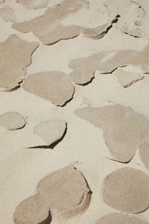 a pile of rocks sitting on top of a sandy beach, an album cover, inspired by Kuno Veeber, sand color, subtle pattern, sidewalk, sandy beige