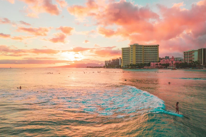 a man riding a surfboard on top of a wave in the ocean, colorful buildings, pink clouds, waikiki beach, instagram post