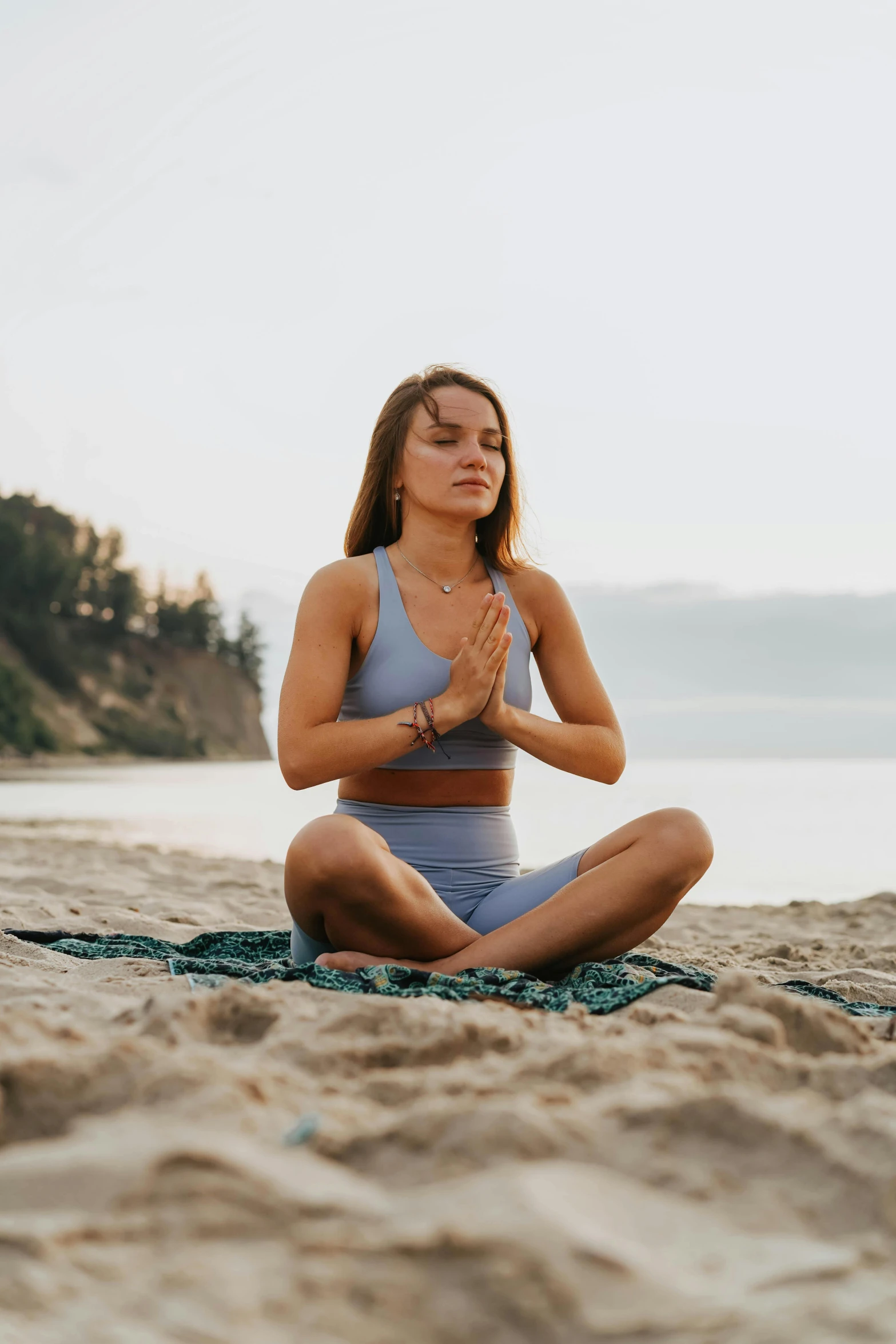 a woman is doing yoga on the beach, a portrait, unsplash, sitting with wrists together, chillwave, low quality photo, concern