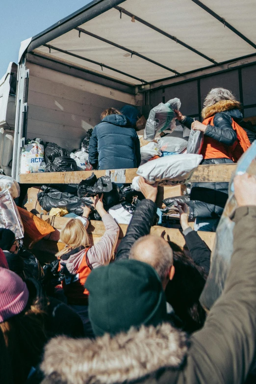 a group of people that are standing in front of a truck, by Matija Jama, trending on unsplash, temporary emergency shelter, crowds panic, clothing drop, winter sun