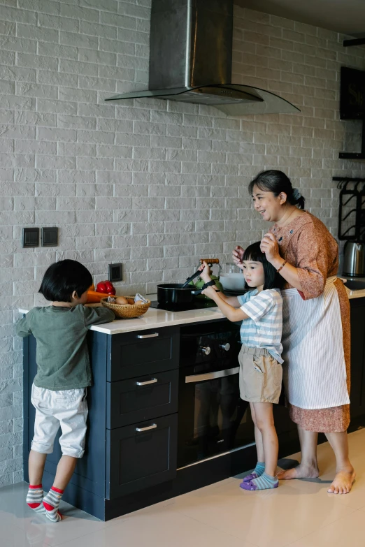 a woman standing next to two children in a kitchen, pexels contest winner, steaming food on the stove, joy ang, gif, boys