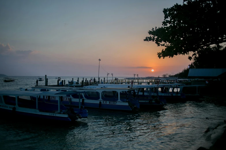 a group of boats sitting on top of a body of water, happening, the sunset, near a jetty, ramil sunga, portrait photo