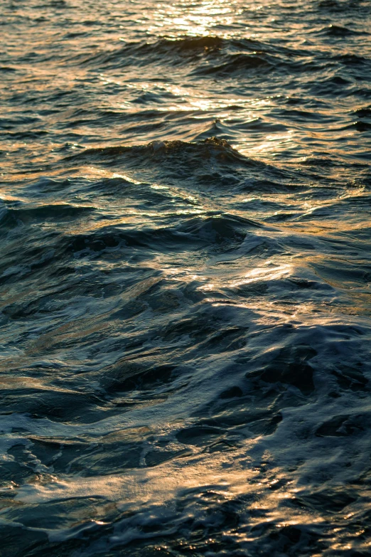 the sun is setting over a body of water, inspired by Elsa Bleda, hyperrealism, turbulent waves, ignant, gold and indigo, a close-up