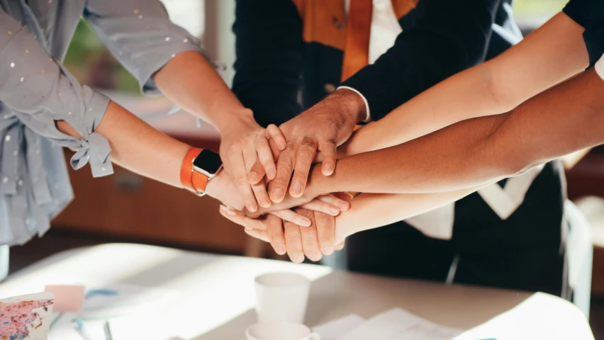 a group of people putting their hands together, a cartoon, trending on pexels, corporate photo, hand on table, background image, multiple stories