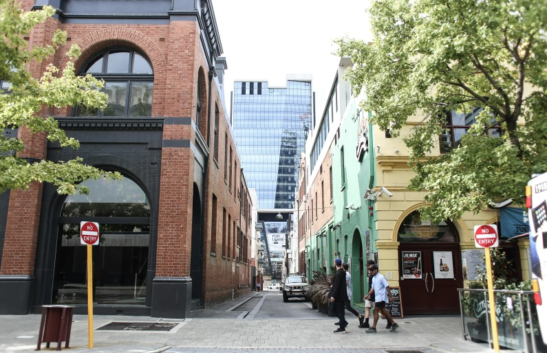 a group of people walking down a street next to tall buildings, alleyway, green square, william warehouse, buildings made out of glass