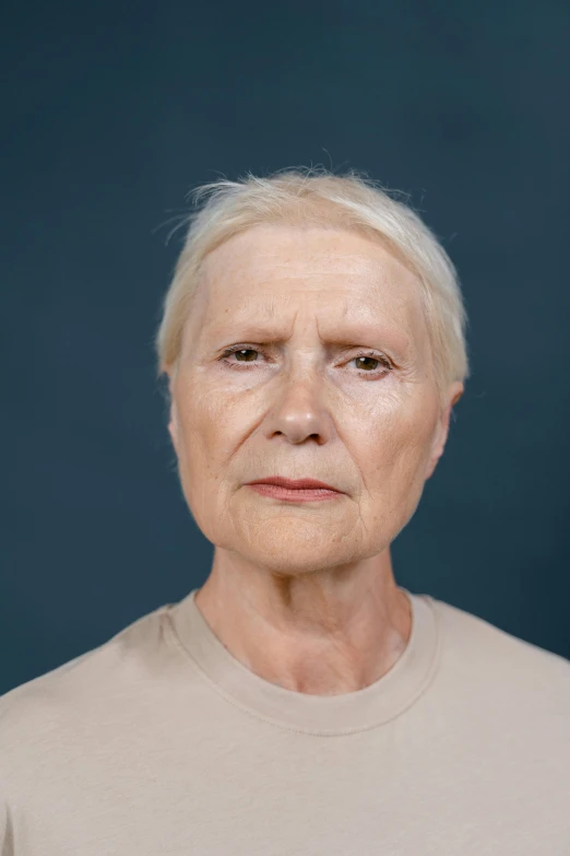 an older woman standing in front of a blue background, a character portrait, by Marina Abramović, hyperrealism, on clear background, realistic restored face, nonbinary model, realistic | detailed face