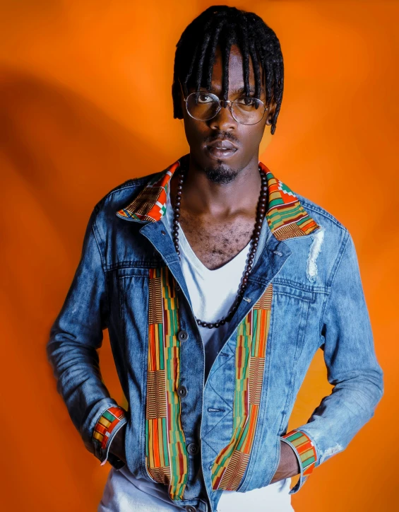 a man standing with his hands in his pockets, an album cover, trending on pexels, afrofuturism, roygbiv, jean jacket, he wears an eyepatch, unmistakably kenyan