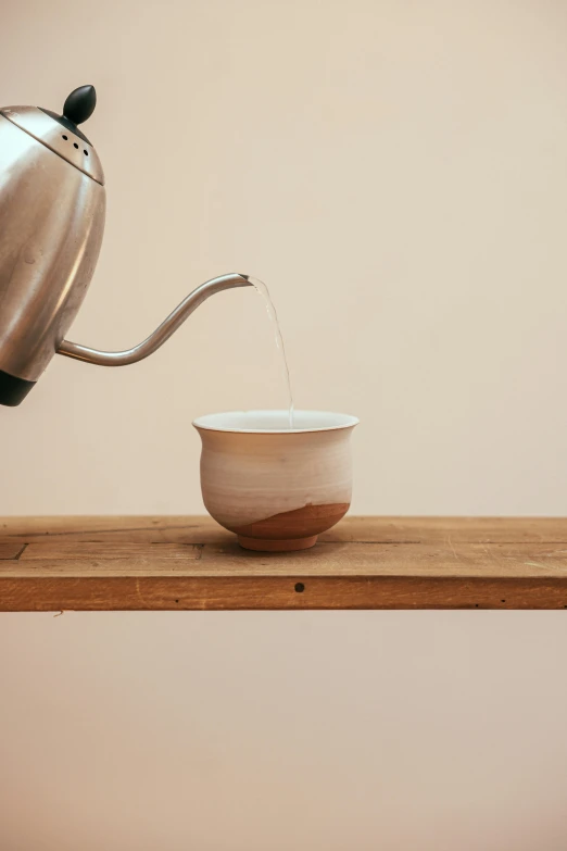 a tea pot pouring water into a cup, inspired by Hendrik Gerritsz Pot, unsplash, process art, gradient brown to white, cedar, handcrafted, minimal