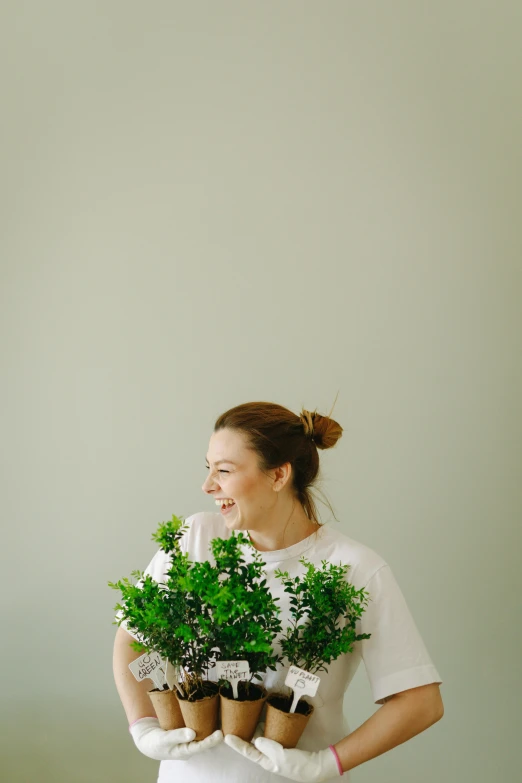 a woman holding a bunch of potted plants, by Carey Morris, pexels contest winner, minimalism, earing a shirt laughing, gif, bouquet, green and white