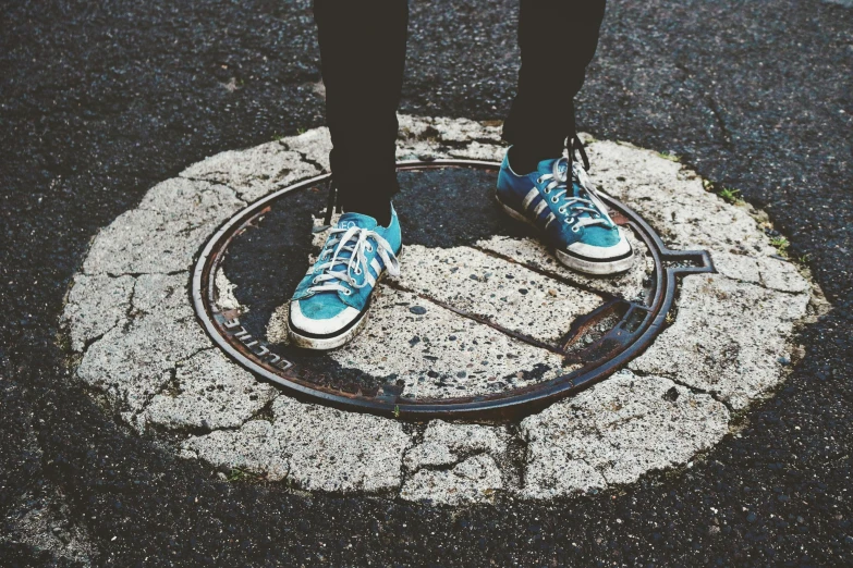 a person standing on top of a manhole, an album cover, pexels contest winner, teenage grunge punk rock, blue shoes, vriska serket, tyre mark