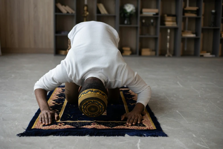 a man is doing a handstand on a rug, pexels contest winner, hurufiyya, kneeling in prayer, turban, bent over posture, islamic interior design