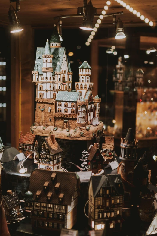 a woman standing in front of a display of miniature buildings, by Jakob Gauermann, pexels contest winner, fantasy bakery, holiday season, with castle in distance, gif