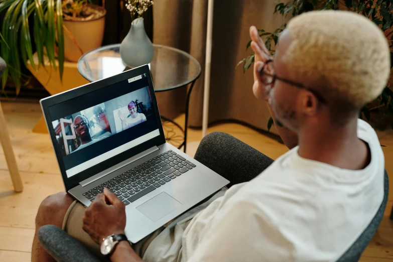 a man sitting in a chair using a laptop computer, pexels contest winner, video art, black man, parents watching, connection rituals, long distance photo