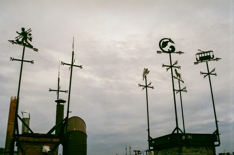 a group of weather vanes sitting on top of a roof, by Carey Morris, unsplash, shipyard, green smoggy sky, ignant, vintage photo