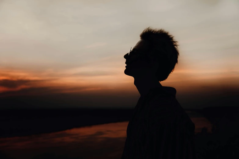 a silhouette of a person standing in front of a sunset, profile image, androgynous male, trending photo, thin face