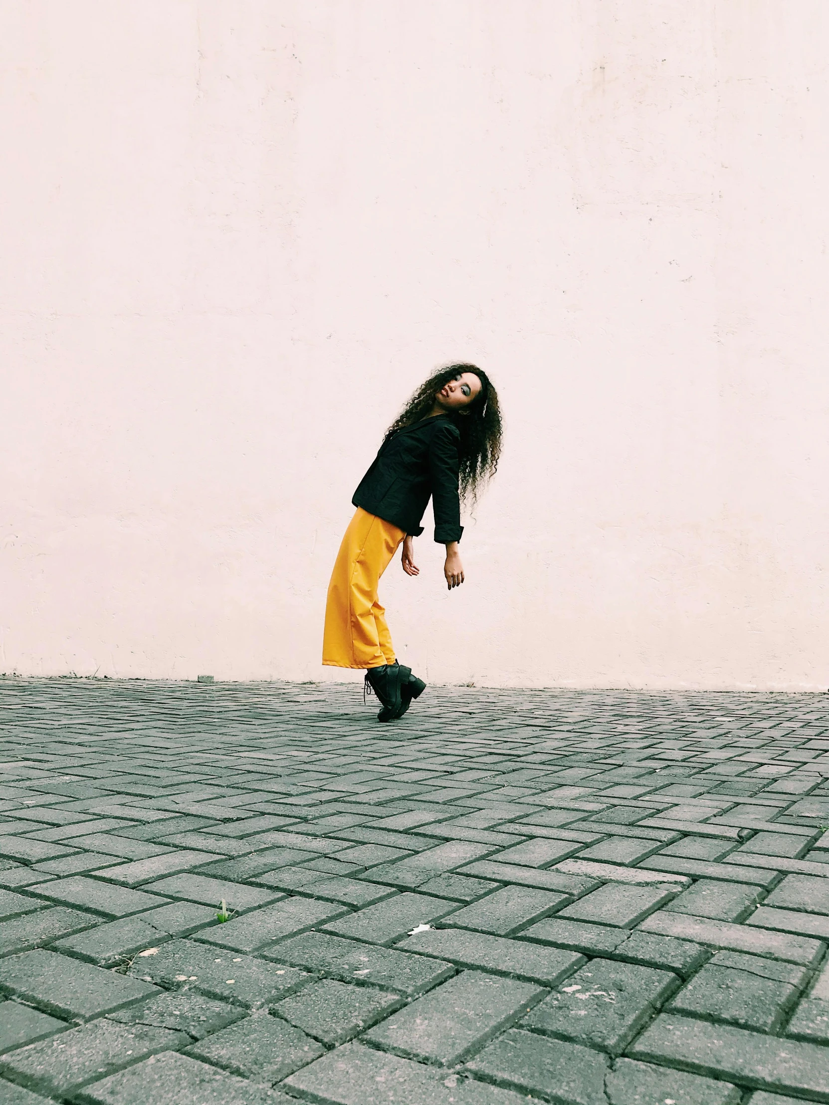 a woman in a black shirt and yellow pants, a picture, by Pablo Rey, unsplash, happening, bipedal, dressed with long fluent clothes, in a square, profile image