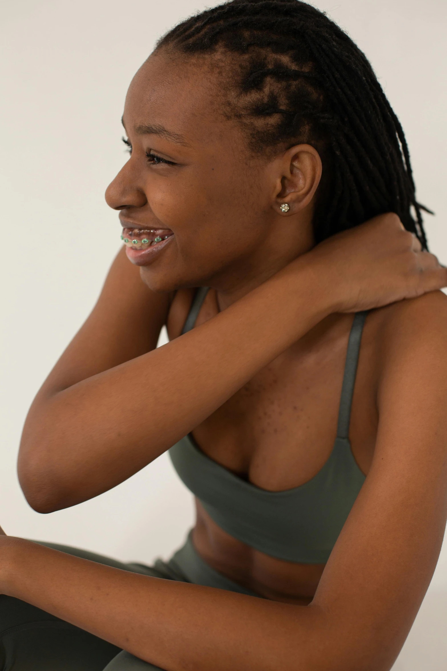 a woman sitting on the floor using a laptop computer, by Matija Jama, trending on unsplash, head bent back in laughter, pale green halter top, with brown skin, sport bra and shirt