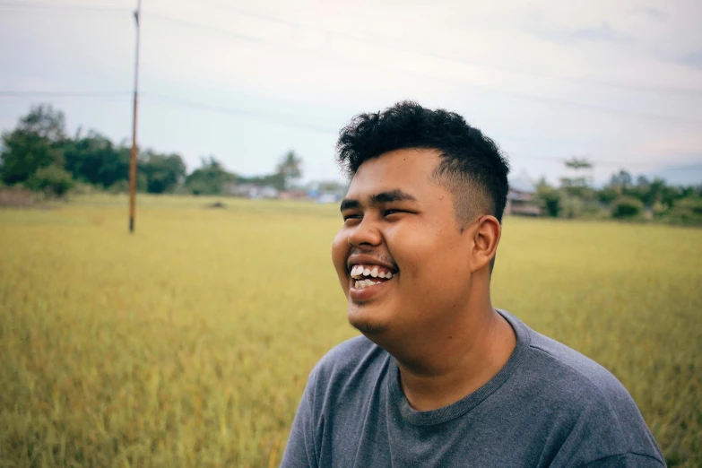 a man smiles while standing in a field, pexels contest winner, sumatraism, male teenager, avatar image, big chin, profile image