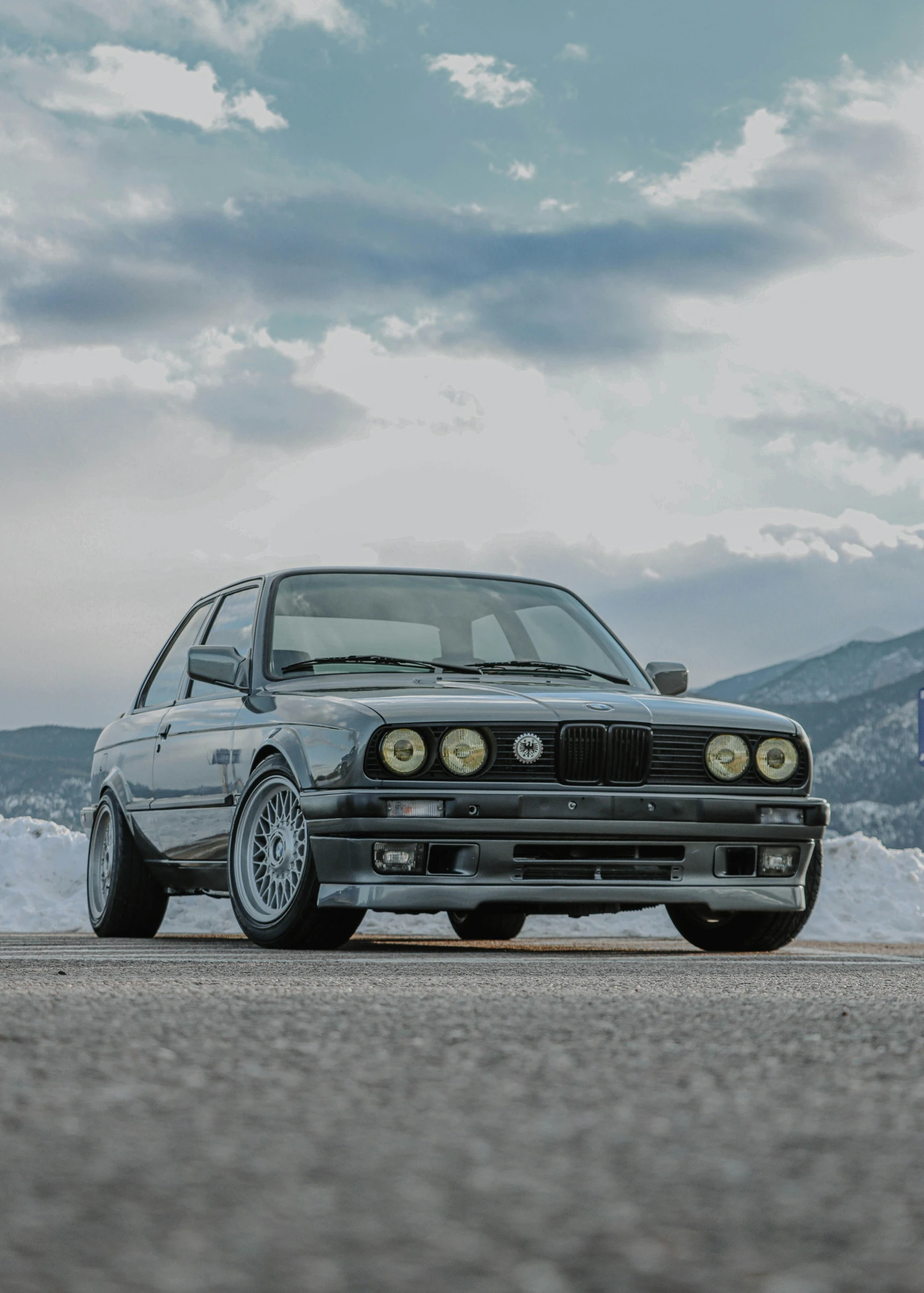 a couple of cars parked next to each other on a road, a portrait, pexels contest winner, renaissance, bmw e 3 0, winter, profile image, with mountains in background