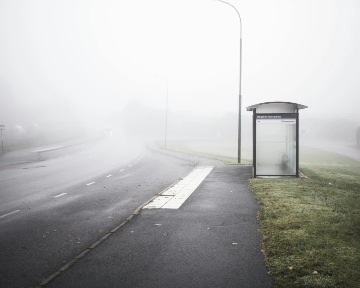 a bus stop sitting on the side of a road, inspired by Pierre Pellegrini, pexels contest winner, light grey mist, in a suburb, water mist, bus stop