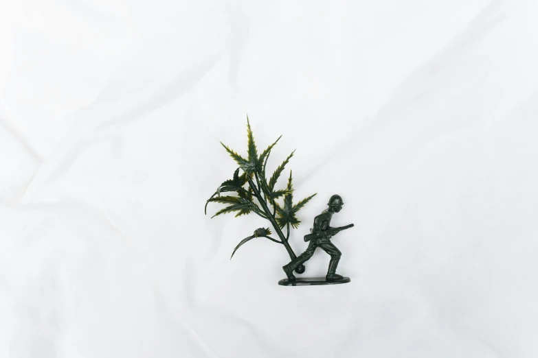 a figurine of a man holding a plant, a statue, inspired by Banksy, unsplash, dead soldiers on the battlefield, white minimalistic background, on the bed, seen from straight above