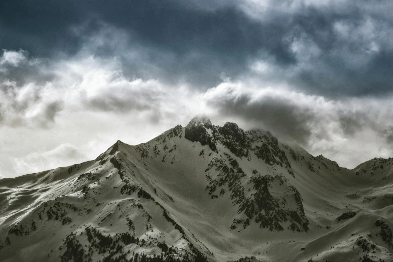 a mountain covered in snow under a cloudy sky, by Cedric Peyravernay, pexels contest winner, fine art print, dramatic ”