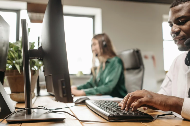 a man sitting at a desk in front of a computer, trending on pexels, hurufiyya, in an call centre office, mechanical keyboard, avatar image, a wooden