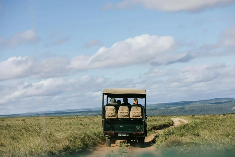 a group of people riding in the back of a truck, by Jessie Algie, unsplash, hurufiyya, bushveld background, kauai, manuka, luxury