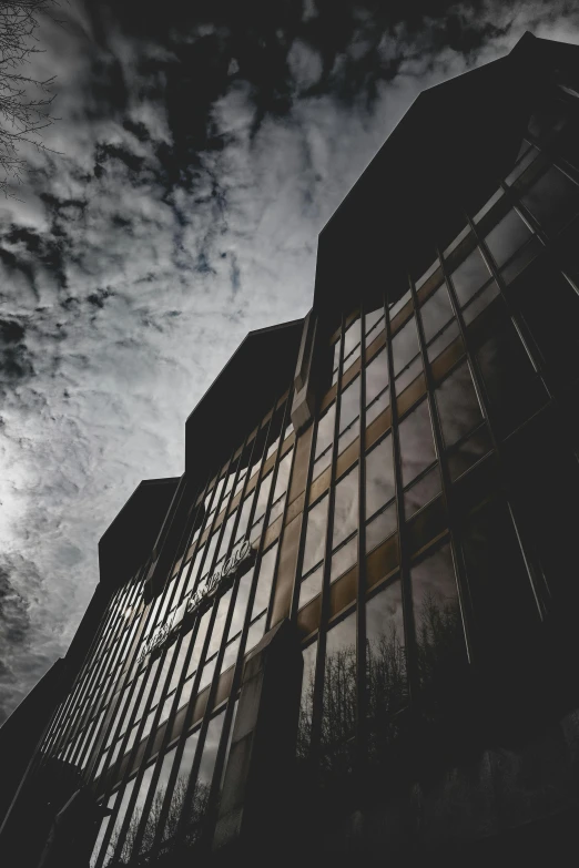 a tall building with lots of windows under a cloudy sky, pexels contest winner, brutalism, dark and mysterious, high quality photo, dramatic lighting - n 9, wideangle