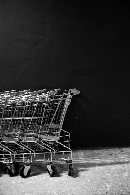 a black and white photo of a row of shopping carts, inspired by Arnold Newman, with a black background, promo image, hunger, game