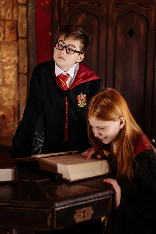 a couple of kids that are looking at a book, by Fuller Potter, wearing wizard robes, promo image, indoor setting, magic uniform