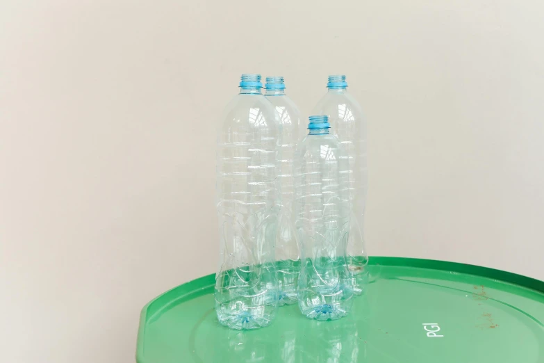 three empty water bottles sitting on top of a green table, by Nathalie Rattner, plasticien, andré le nôtre, light blue water, 2 meters, pack