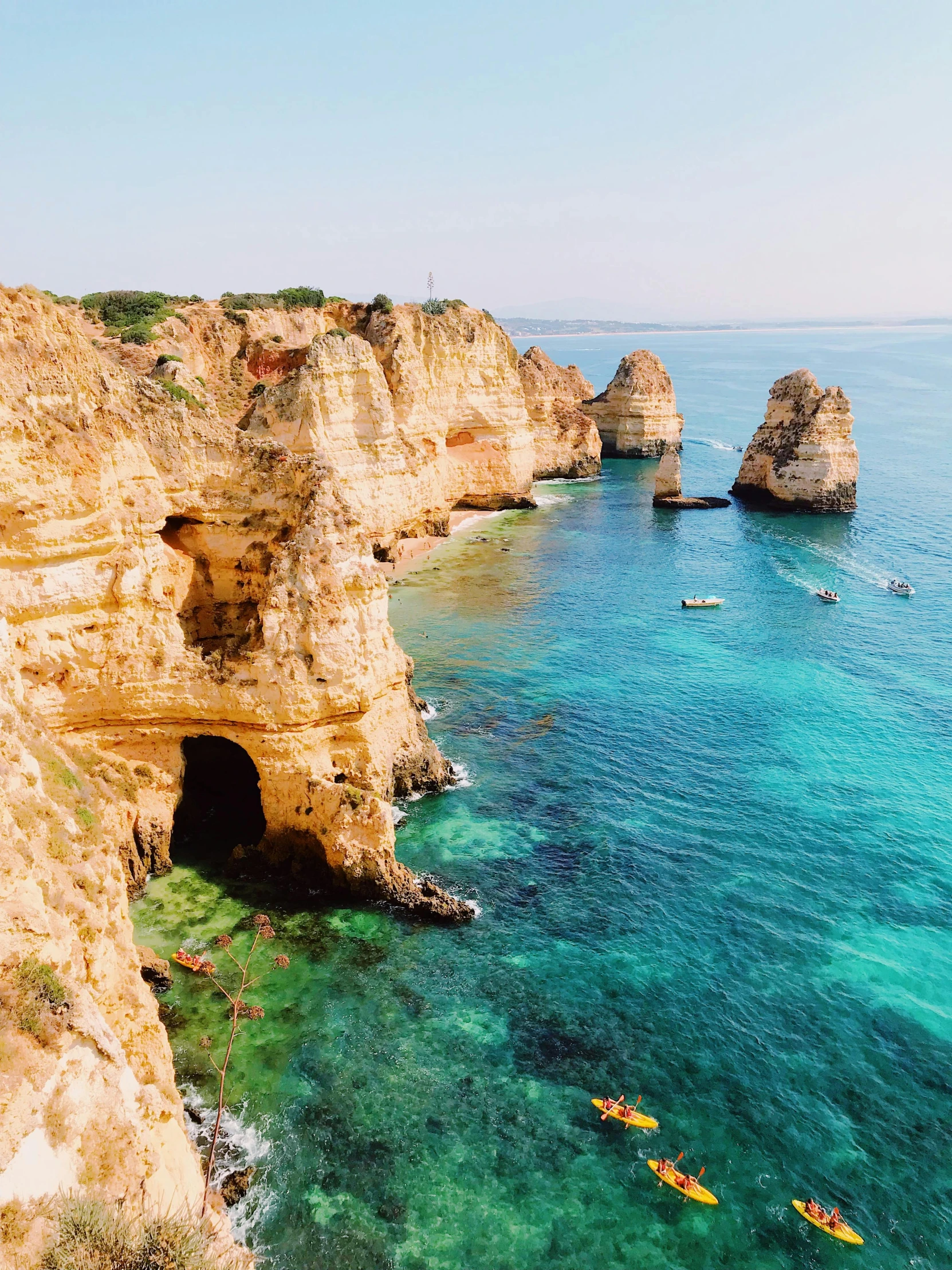 a couple of kayaks that are in the water, pexels contest winner, sheer cliffs surround the scene, rocha, conde nast traveler photo, slide show