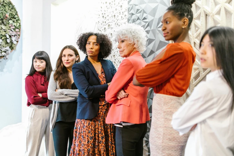 a group of women standing next to each other, by Matija Jama, trending on pexels, renaissance, concerned, in a workshop, wearing business casual dress, patterned