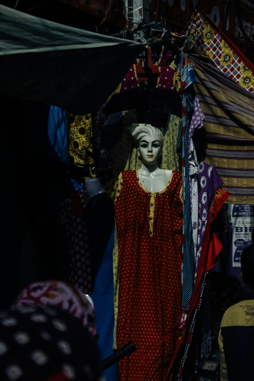 a statue of a woman in a red dress, inside an arabian market bazaar, scary night, somali attire, in front of a black background