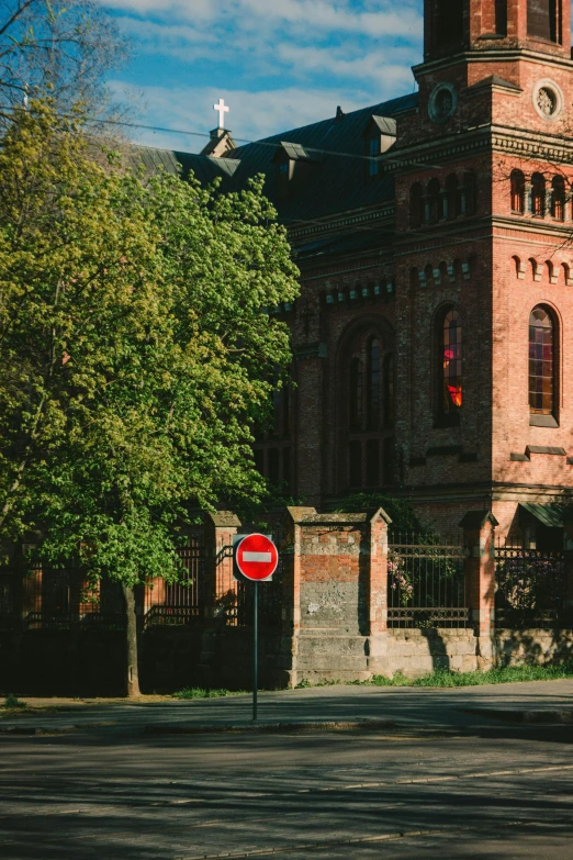 a large brick building with a clock tower, a picture, pexels contest winner, heidelberg school, dappled in evening light, private academy entrance, view from the street, an overgrown library