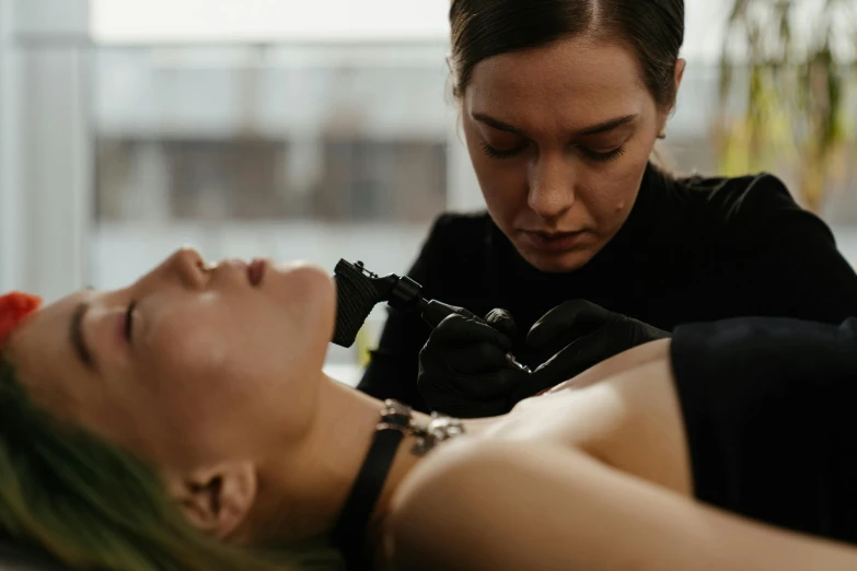 a woman getting a tattoo on another woman's face, by Lee Loughridge, trending on pexels, hyperrealism, lying down, cinestill colour cinematography, te pae, body and torso