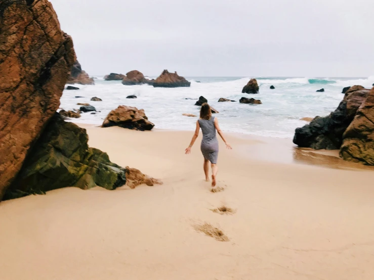 a woman walking along a sandy beach next to the ocean, pexels contest winner, malibu canyon, running freely, instagram post, thumbnail