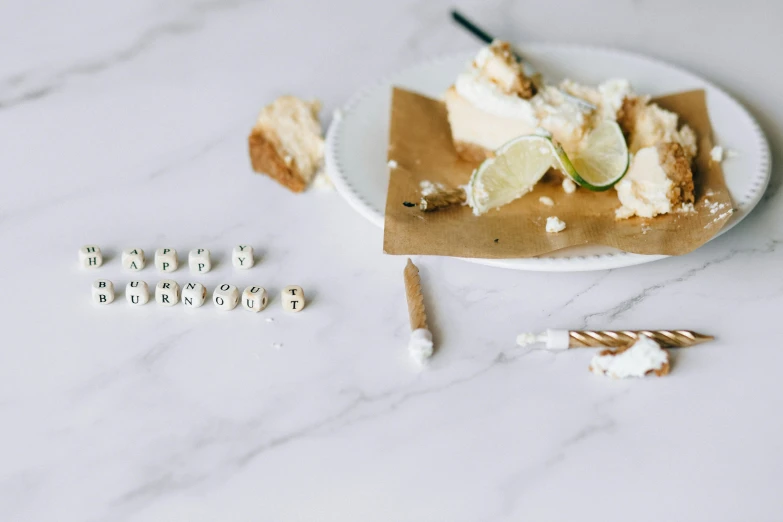 a piece of pie sitting on top of a white plate, a marble sculpture, trending on unsplash, letterism, happy birthday candles, white stones, funny jumbled letters, white gold color palette